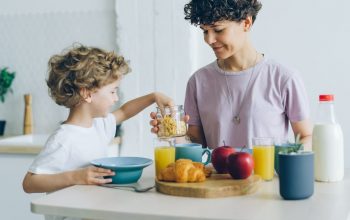 Happy family mother and son eating cereal with milk at home talking
